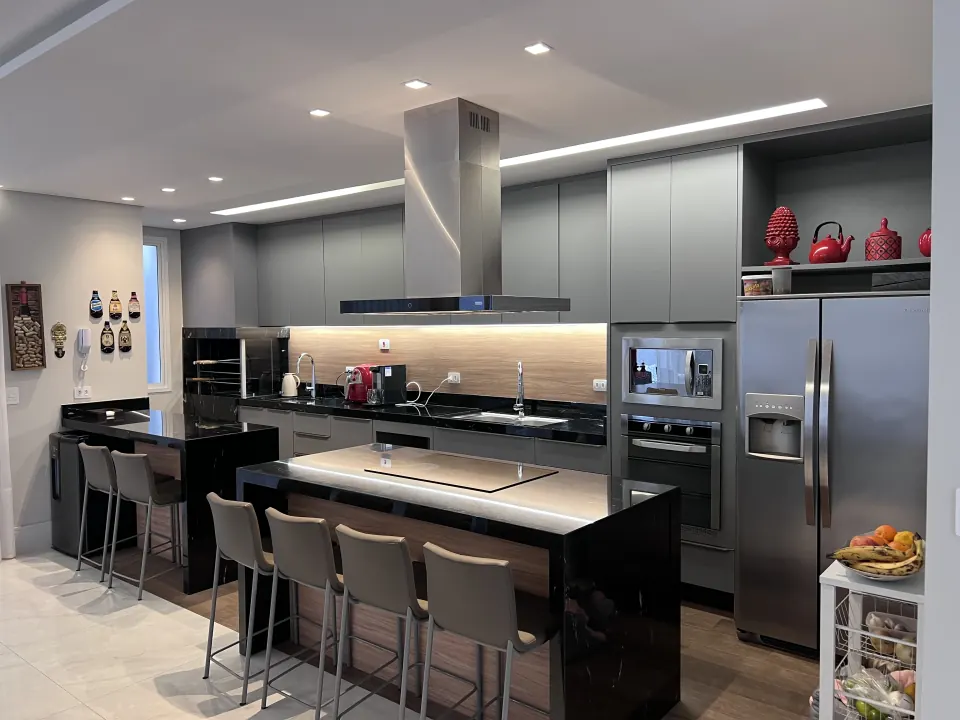 Cozinha gourmet planejada em tom grafite com ilha central, coifa embutida e torre quente