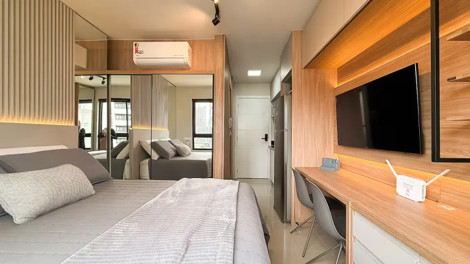 Suíte planejada com painel de TV ripado, bancada de trabalho e espelho integrado